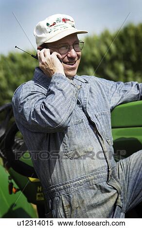 Man leaning against tractor talking on cell phone View Large Photo Image Stock Photography - Man leaning against tractor talking on cell phone. Fotosearch