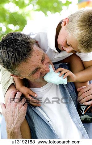 Stock Photo - Boy feeding man cotton candy. Fotosearch