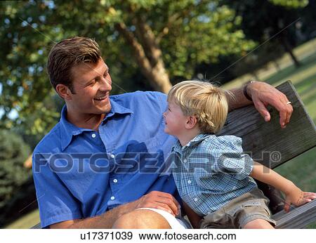 Stock Photo - Dad and son sitting on park bench. Fotosearch
