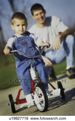 Dad watching son on tricycle View Large Photo Image Stock Photo - Dad watching son on tricycle. Fotosearch