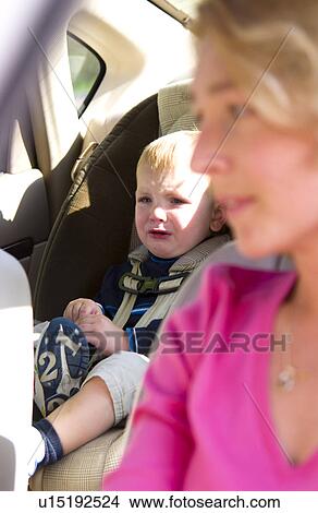 Mom driving with child in car safety seat View Large Photo Image Picture - Mom driving with child in car safety seat. Fotosearch