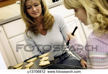 Stock Image - Mother and daughter baking cookies. Fotosearch