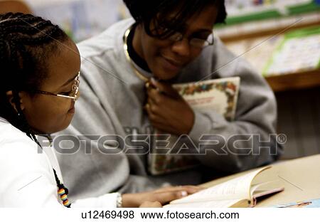 Stock Photo - Teacher helping student with schoolwork. Fotosearch