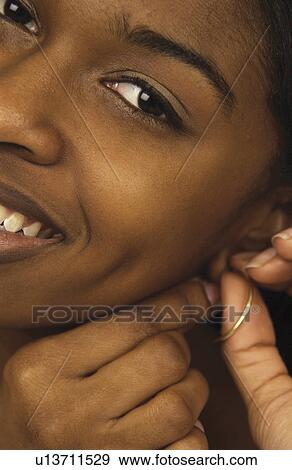 Stock Photo - Woman putting on earring. Fotosearch