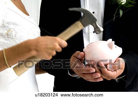 Picture - Bride and groom breaking piggy bank. Fotosearch