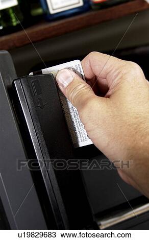 Stock Image - Mans hand swiping credit card through cash register. Fotosearch