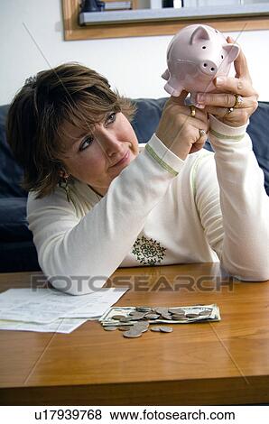 Stock Photo - Woman raiding piggy bank. Fotosearch