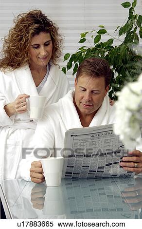 Stock Photography - Couple sitting at table reading newspaper. Fotosearch