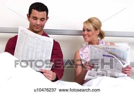 Stock Photo - Couple in bed reading newspaper. Fotosearch