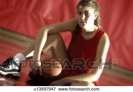 Stock Photo - Girl sitting on the gym floor with a basketball. Fotosearch