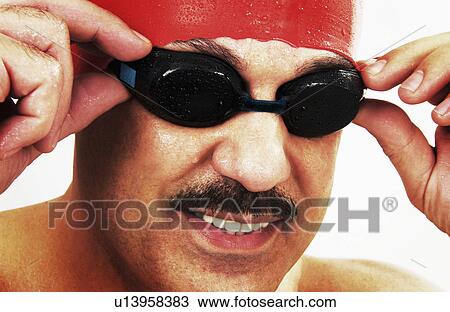Stock Image - Man putting on swimming goggles. Fotosearch