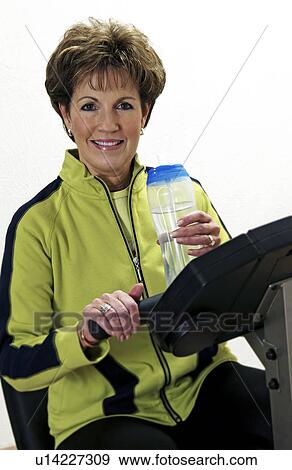 Stock Photo - Senior woman exercising on exercise bike. Fotosearch