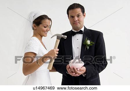 Bride and groom breaking piggy bank View Large Photo Image Stock Photo - Bride and groom breaking piggy bank. Fotosearch