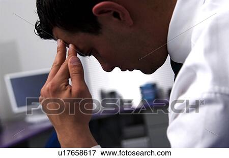 Stock Photo - Businessman at desk with headache. Fotosearch