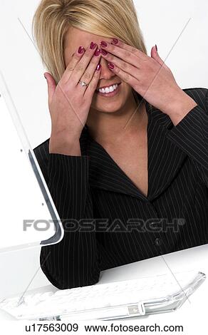 Stock Photo - Businesswoman at computer hiding her eyes. Fotosearch