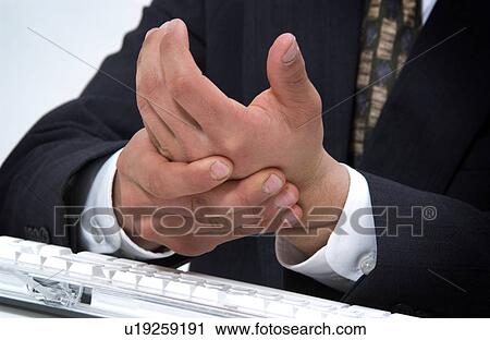 Stock Image - Man at computer rubbing his tired hands. Fotosearch