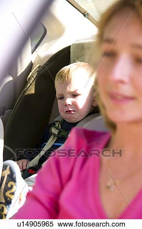 Stock Photography - Mom driving with child in car safety seat. Fotosearch