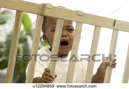 Toddler behind a baby gate View Large Photo Image Stock Photo - Toddler behind a baby gate. Fotosearch