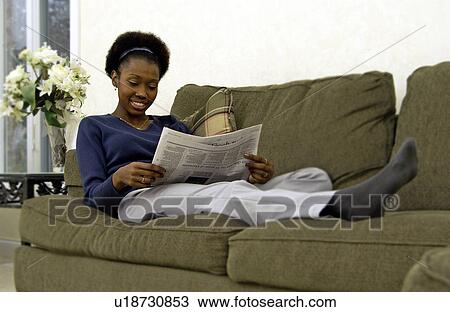 Stock Image - African American woman reading newspaper. Fotosearch