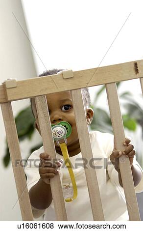 Toddler behind a baby gate View Large Photo Image Stock Photo - Toddler behind a baby gate. Fotosearch