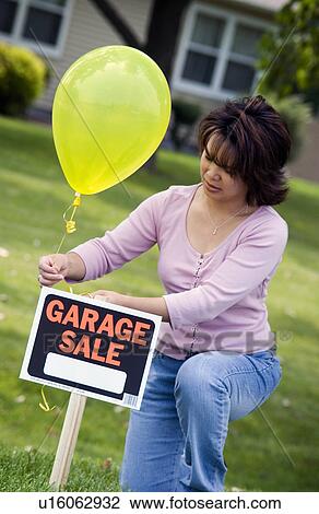 Woman putting up garage sale sign View Large Photo Image Stock Image - Woman putting up garage sale sign. Fotosearch