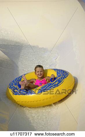 Kid going down water slide on a tube View Large Photo Image Stock Photo - Kid going down water slide on a tube. Fotosearch