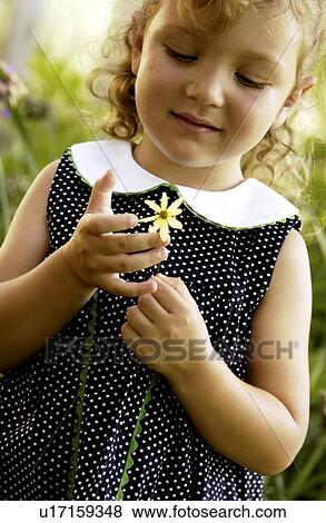 Stock Photo - Little girl holding a flower in her hands. Fotosearch