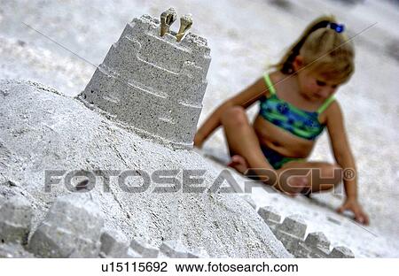 Stock Image - Little girl playing in the sand. Fotosearch