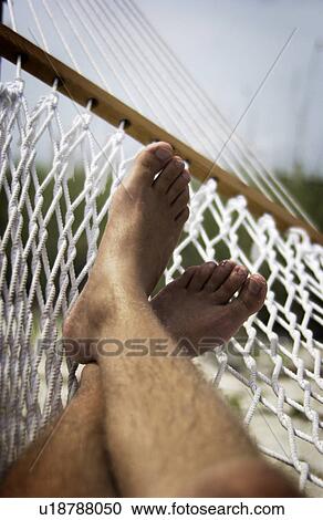 Stock Image - Mans feet on hammock at beach. Fotosearch