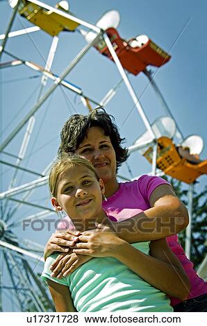 Stock Photo - Mother and daughter at carnival in front of ferris wheel. Fotosearch