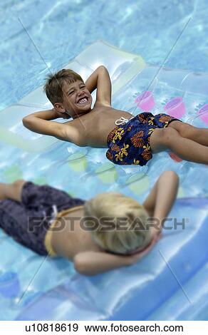 Two boys floating on rafts in a pool View Large Photo Image Stock Photo - Two boys floating on rafts in a pool. Fotosearch