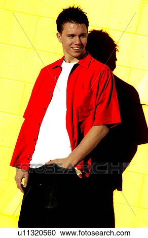 Stock Image - Teenager leaning against a yellow wall. Fotosearch