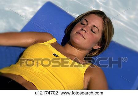Stock Image - Woman lying on raft in pool. Fotosearch