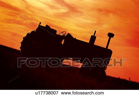 Stock Photo - Tractor in field at sunset. Fotosearch