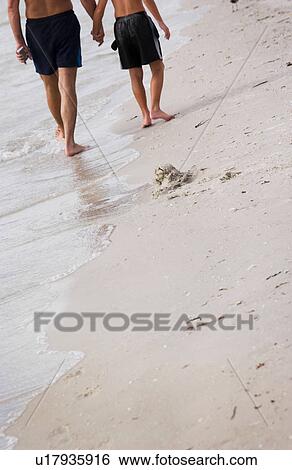 Stock Photograph - Father and son walking on beach. Fotosearch