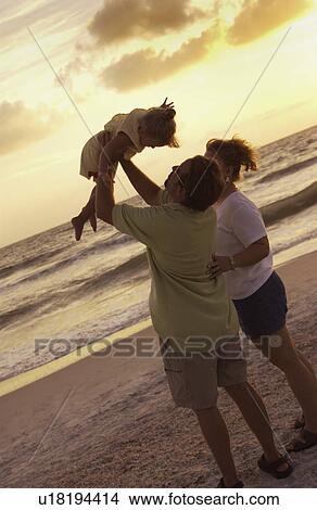 Picture - Mom and dad with daughter on beach. Fotosearch