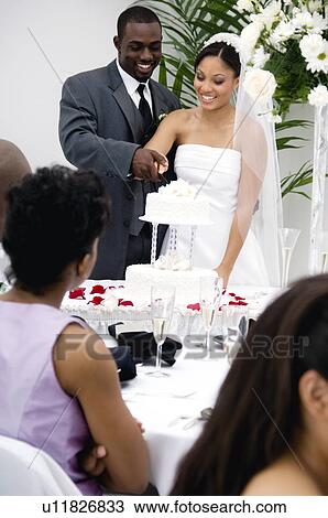 Stock Image - Bride and groom cutting cake. Fotosearch