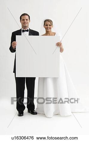 Stock Photograph - Bride and groom holding blank sign. Fotosearch