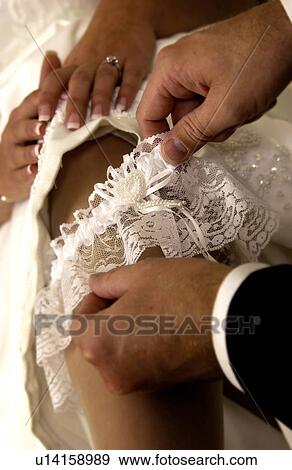 Stock Photo - Groom taking garter off brides leg. Fotosearch