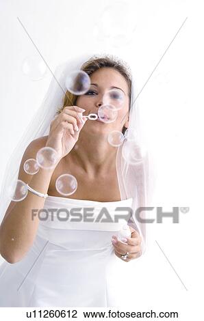Stock Image - Bride blowing bubbles. Fotosearch