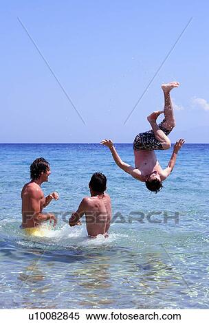 Stock Photography - Young men playing around in the water. Fotosearch