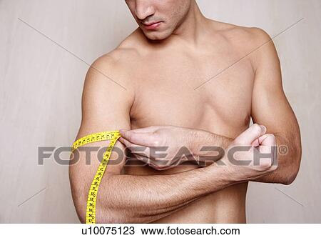 Stock Image - Man measuring his arm muscle. Fotosearch