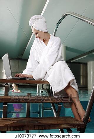 Woman on computer next to a swimming pool View Large Photo Image Stock Photo - Woman on computer next to a swimming pool. Fotosearch