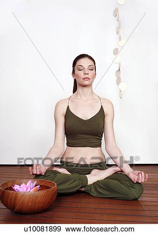 Young woman in a fitness class meditating View Large Photo Image Stock Photo - Young woman in a fitness class meditating. Fotosearch