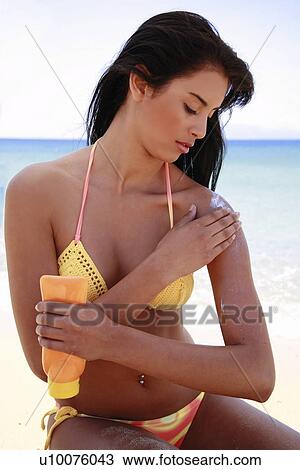 Young woman in bikini applying suntan lotion View Large Photo Image Stock Image - Young woman in bikini applying suntan lotion. Fotosearch
