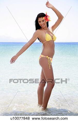 Stock Photo - Young woman posing in the water on beach. Fotosearch