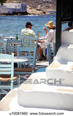 Stock Image - Couple sitting at seaside restaurant table. Fotosearch