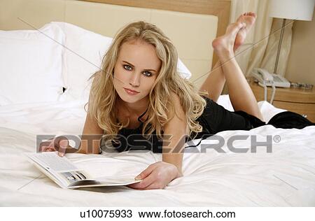 Stock Image - Woman relaxing in bed. Fotosearch