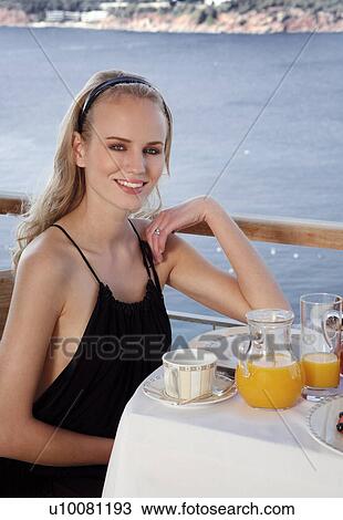 Stock Image - Young woman having breakfast on hotel terrace. Fotosearch