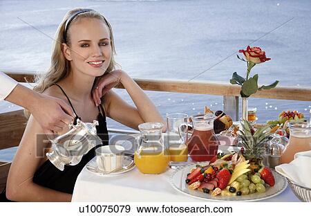 Stock Photo - Young woman having breakfast on hotel terrace. Fotosearch